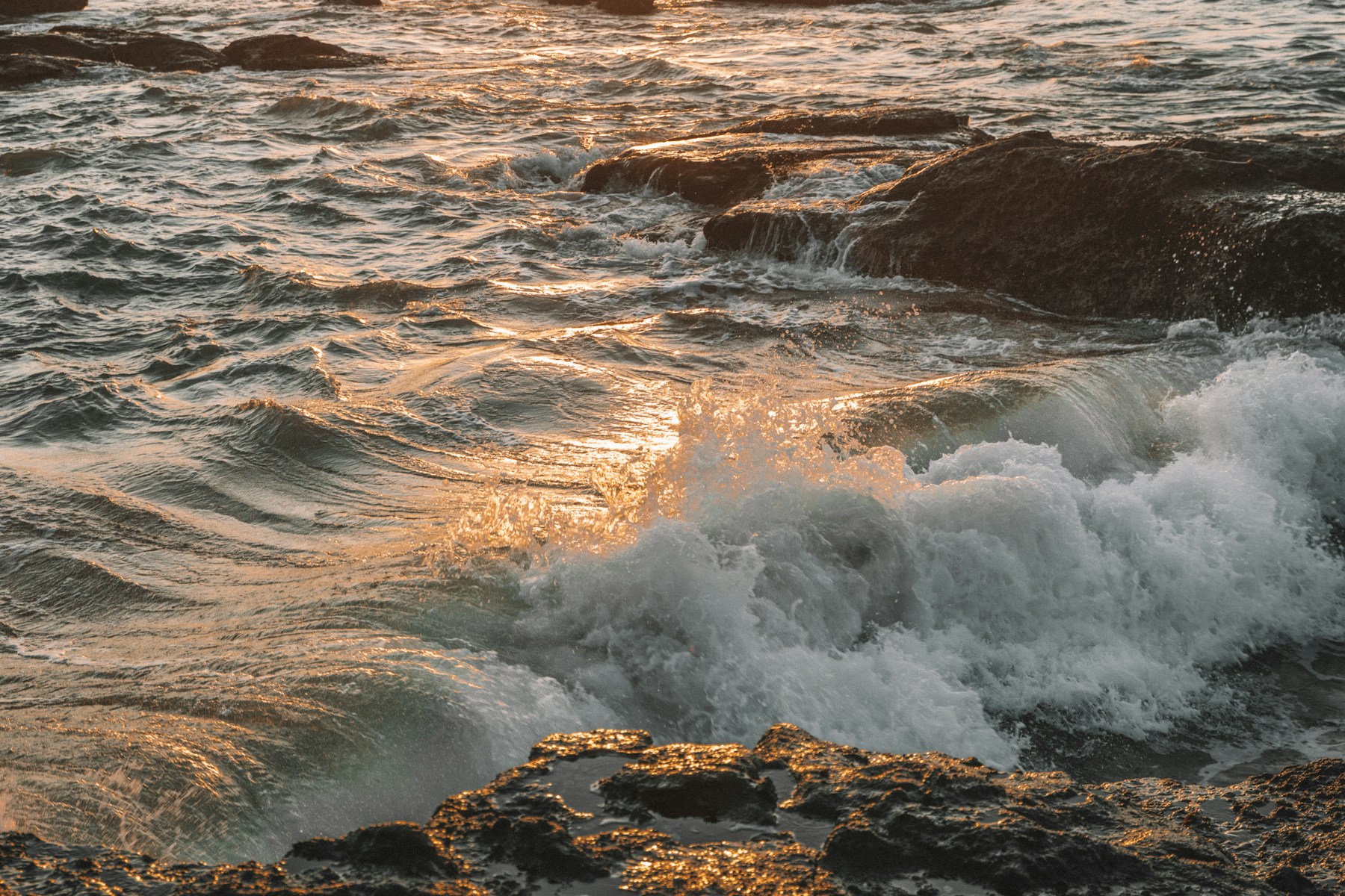 Sunlight on waves breaking against coastal rocks